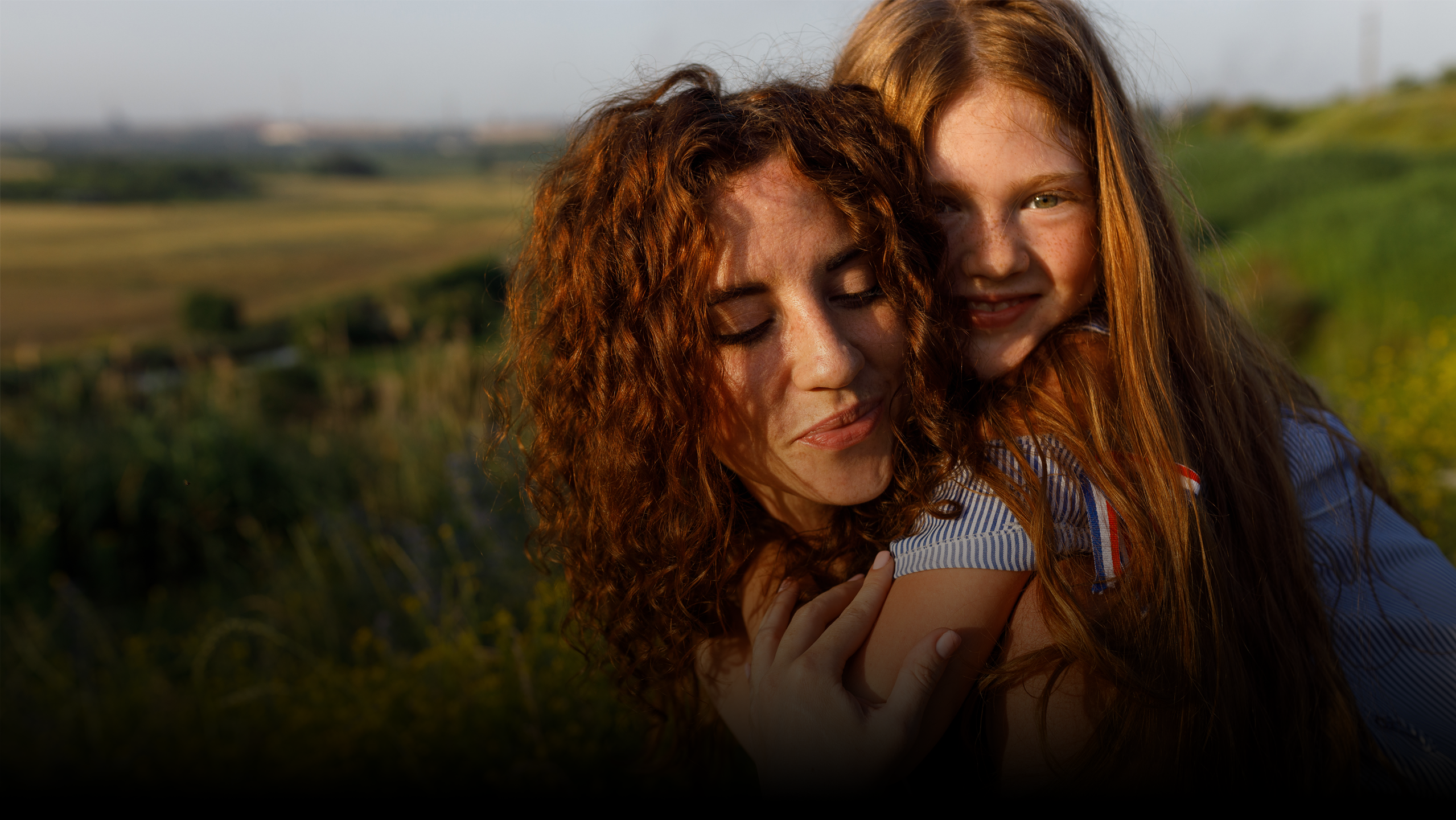 Woman and child looking at a phone together in a field